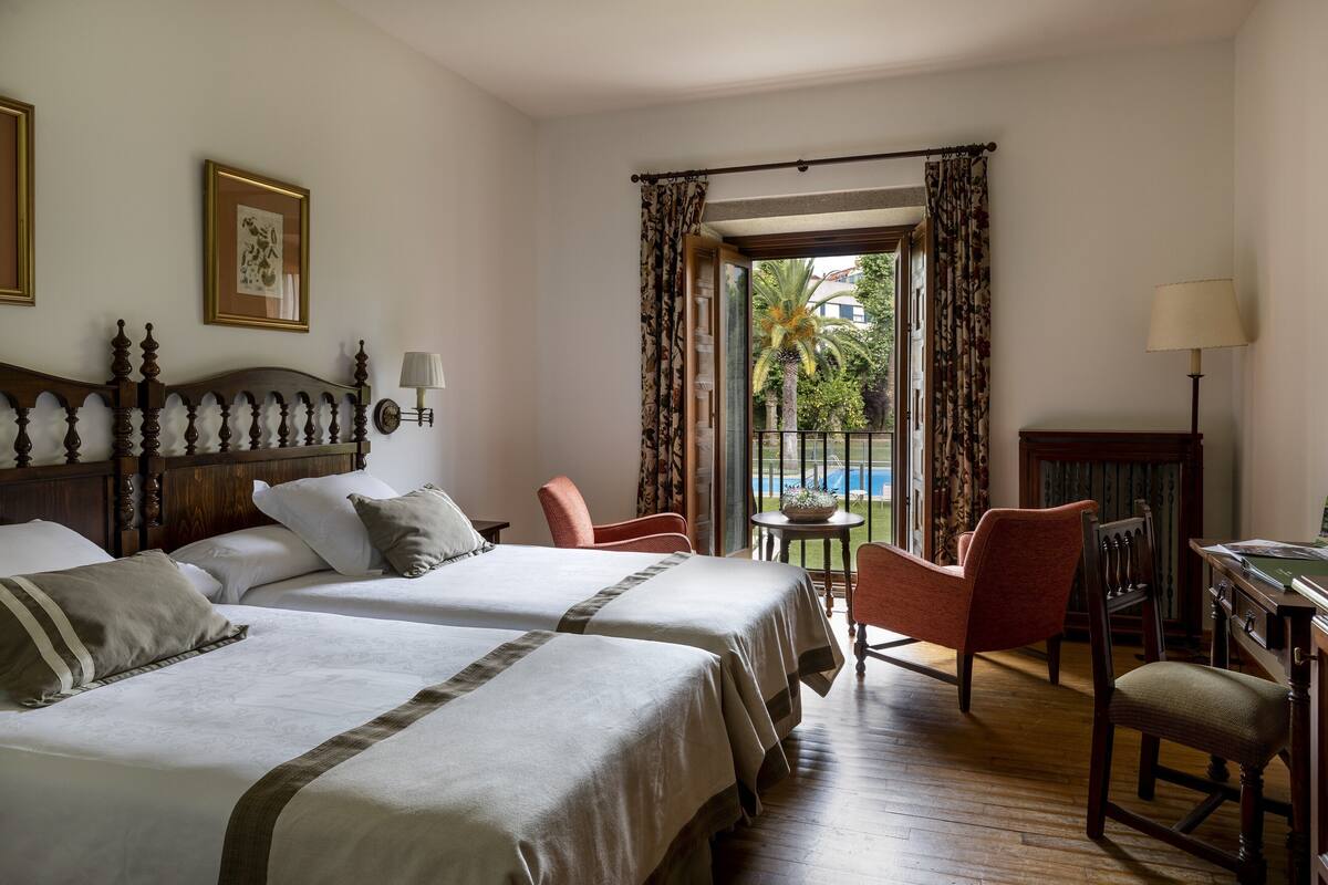 Une chambre d’hôtel avec deux lits, un bureau, une chaise et une vue sur la piscine.