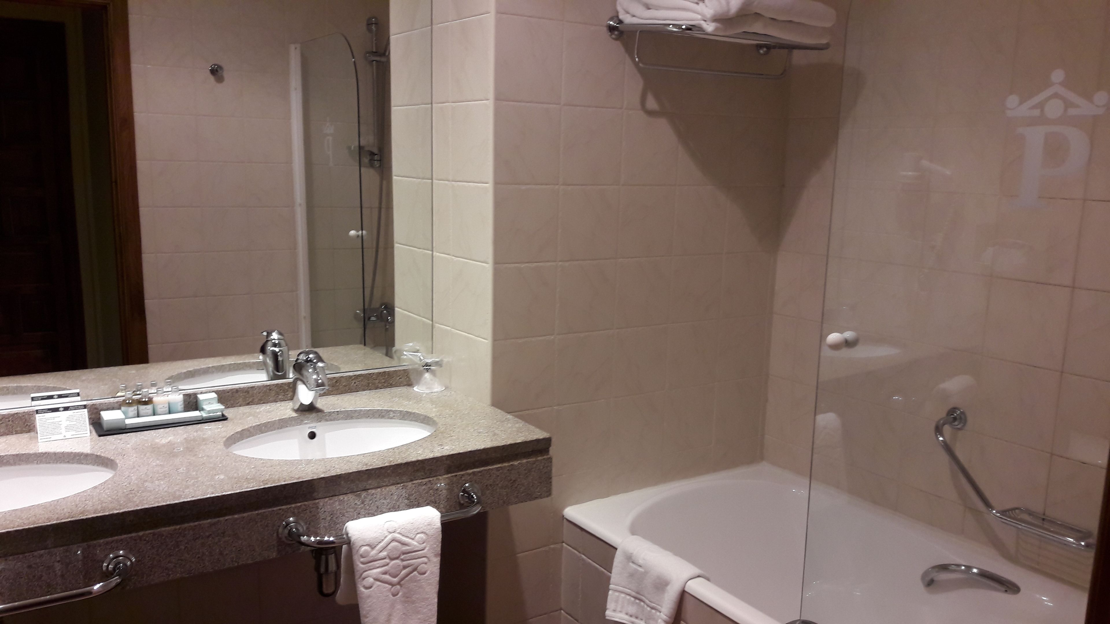 A bathroom with two sinks, a mirror, a bathtub, and a shower.