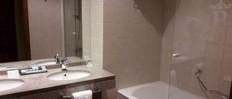 A bathroom with two sinks, a mirror, a bathtub, and a shower.