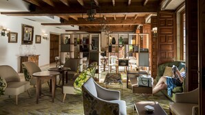 Un salon spacieux avec des poutres apparentes, un canapé, des fauteuils et une table basse.
