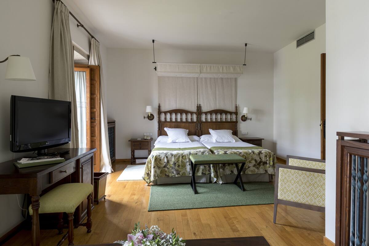 Une chambre à coucher comprenant un lit, des tables de chevet, une télévision et un banc.