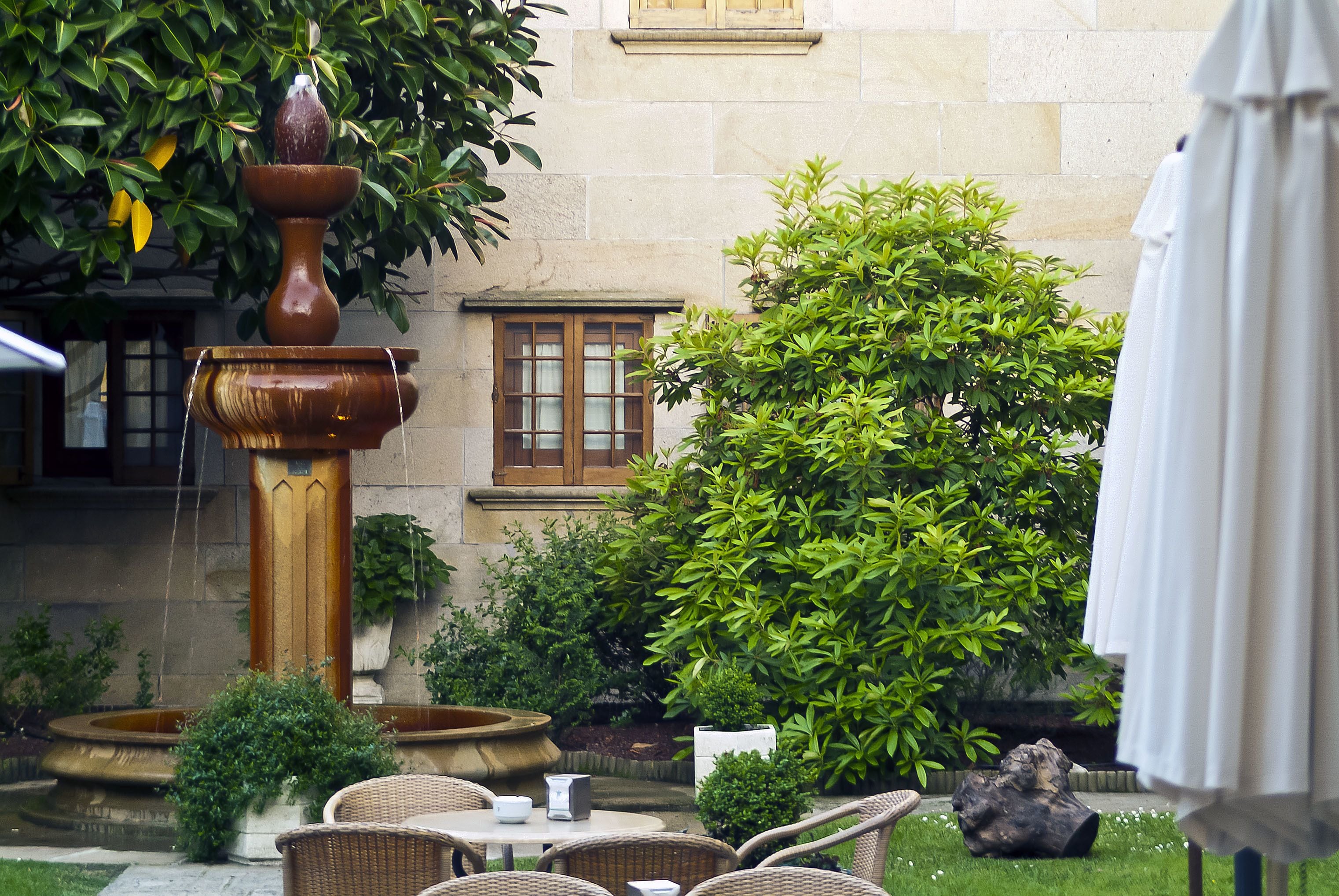 A courtyard with a fountain, outdoor seating, and lush greenery.