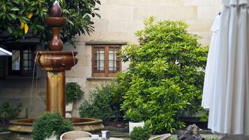 A courtyard with a fountain, outdoor seating, and lush greenery.