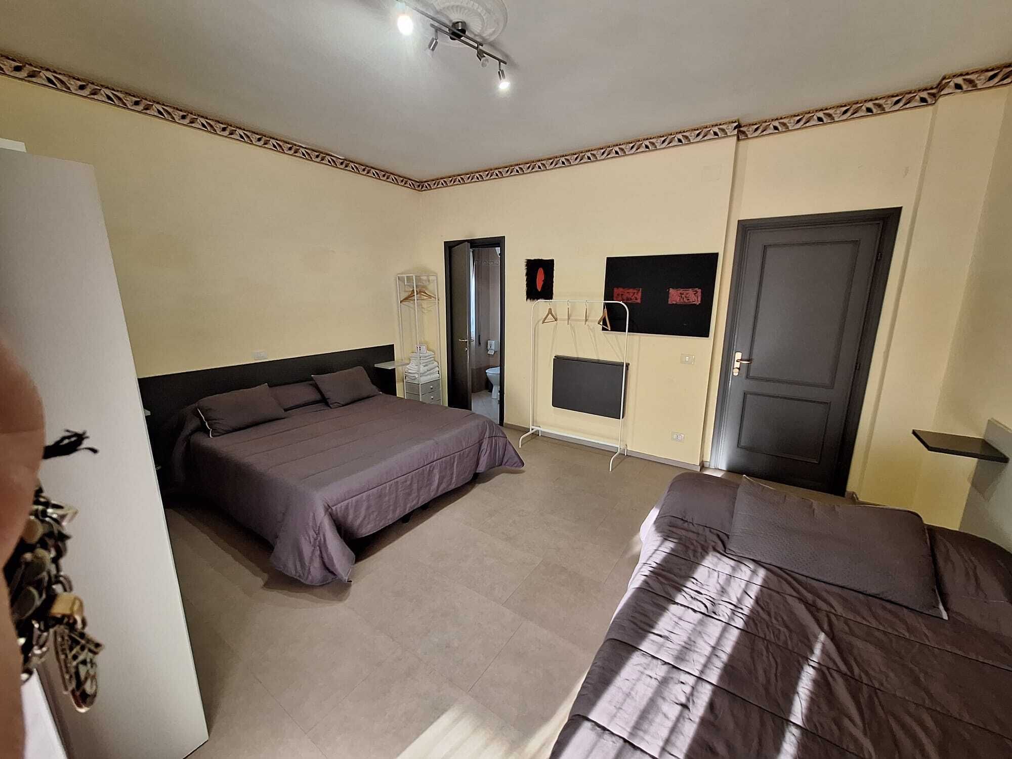 A bedroom with a bed, a bedside table, a wardrobe, a mirror, and a door.