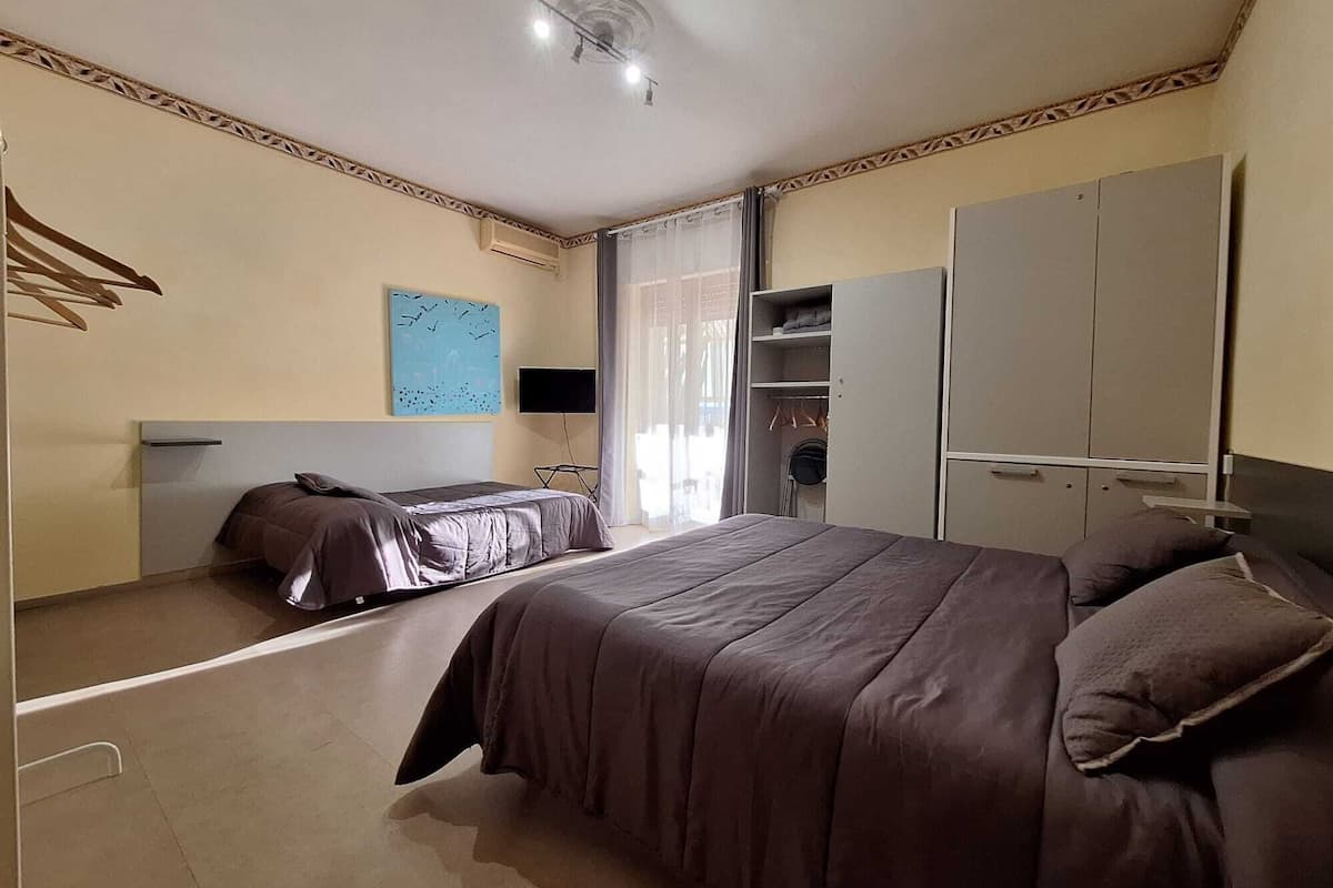 Un dormitorio con dos camas, un armario, un televisor y un cuadro en la pared.