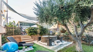 Un patio con mobiliario exterior, una bañera de hidromasaje y un árbol.
