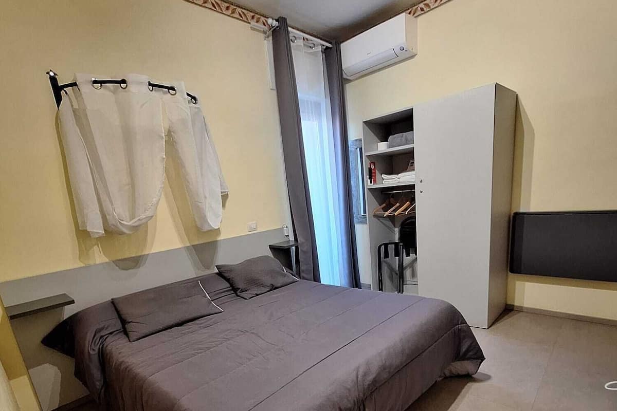 Un dormitorio con una cama grande, un armario, una mesita de noche y un perchero.