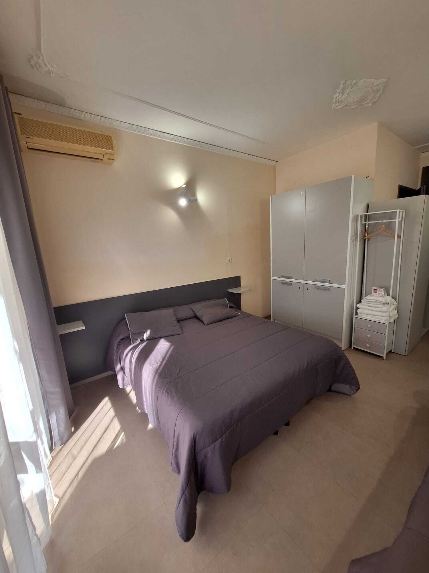Une chambre à coucher comprenant un lit, une armoire et un climatiseur fixé au mur.
