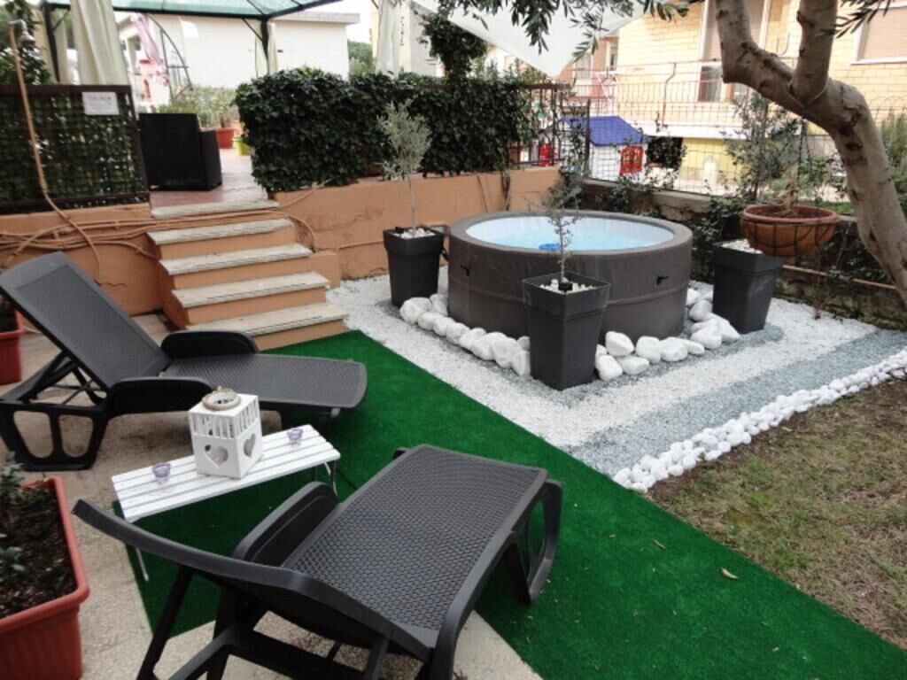 Un espacio al aire libre con un jacuzzi, sillones de descanso y una mesita con un altavoz.