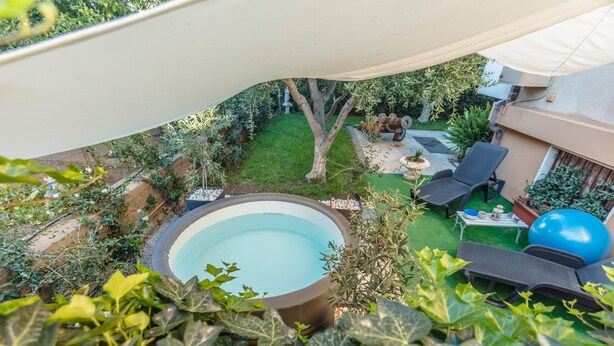 Patio trasero con piscina, sombrilla, mobiliario exterior y pelota de fitness.