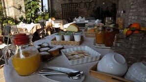 Una mesa de desayuno con diversos alimentos, como pasteles, un jarro de jugo y frascos de conservas.