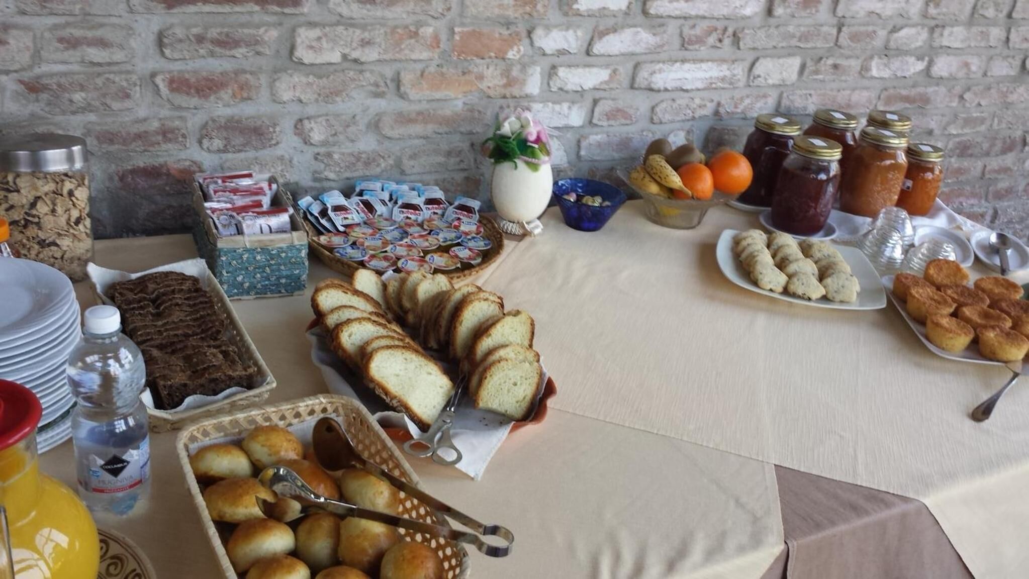 A buffet table with various food items including bread, pastries, and condiments.