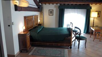 Ein Schlafzimmer mit einem hölzernen Bett, einem Nachttisch, einem Sessel, einem Schreibtisch und einem Fenster mit Vorhängen.