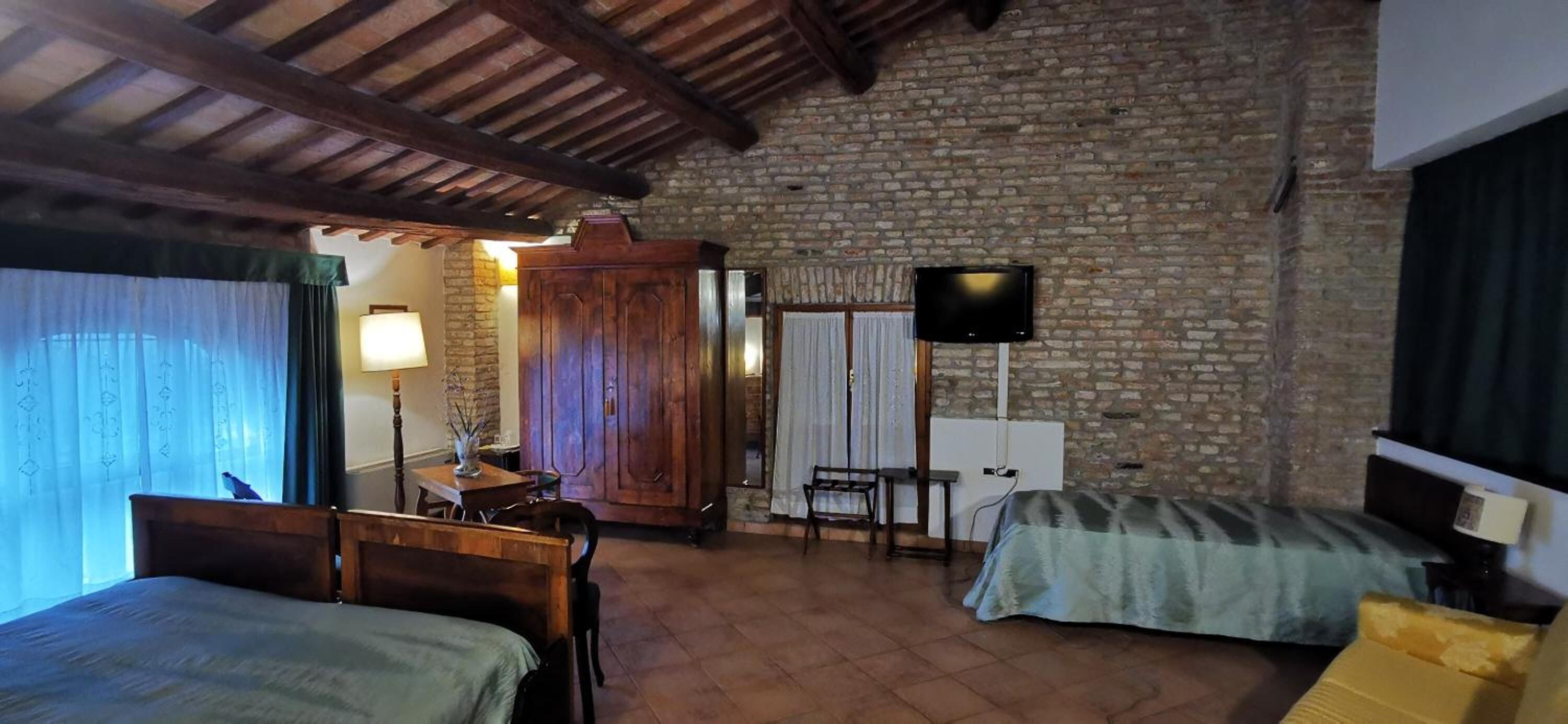 A room with a rustic stone wall, wooden furniture, a television, and a bed.