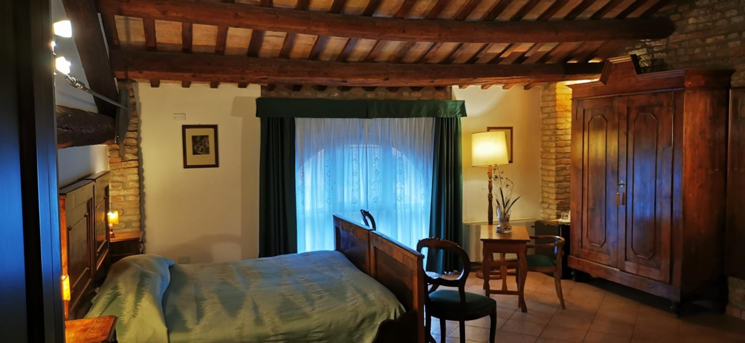 A cozy bedroom with a bed, a chair, a desk, and a wardrobe.