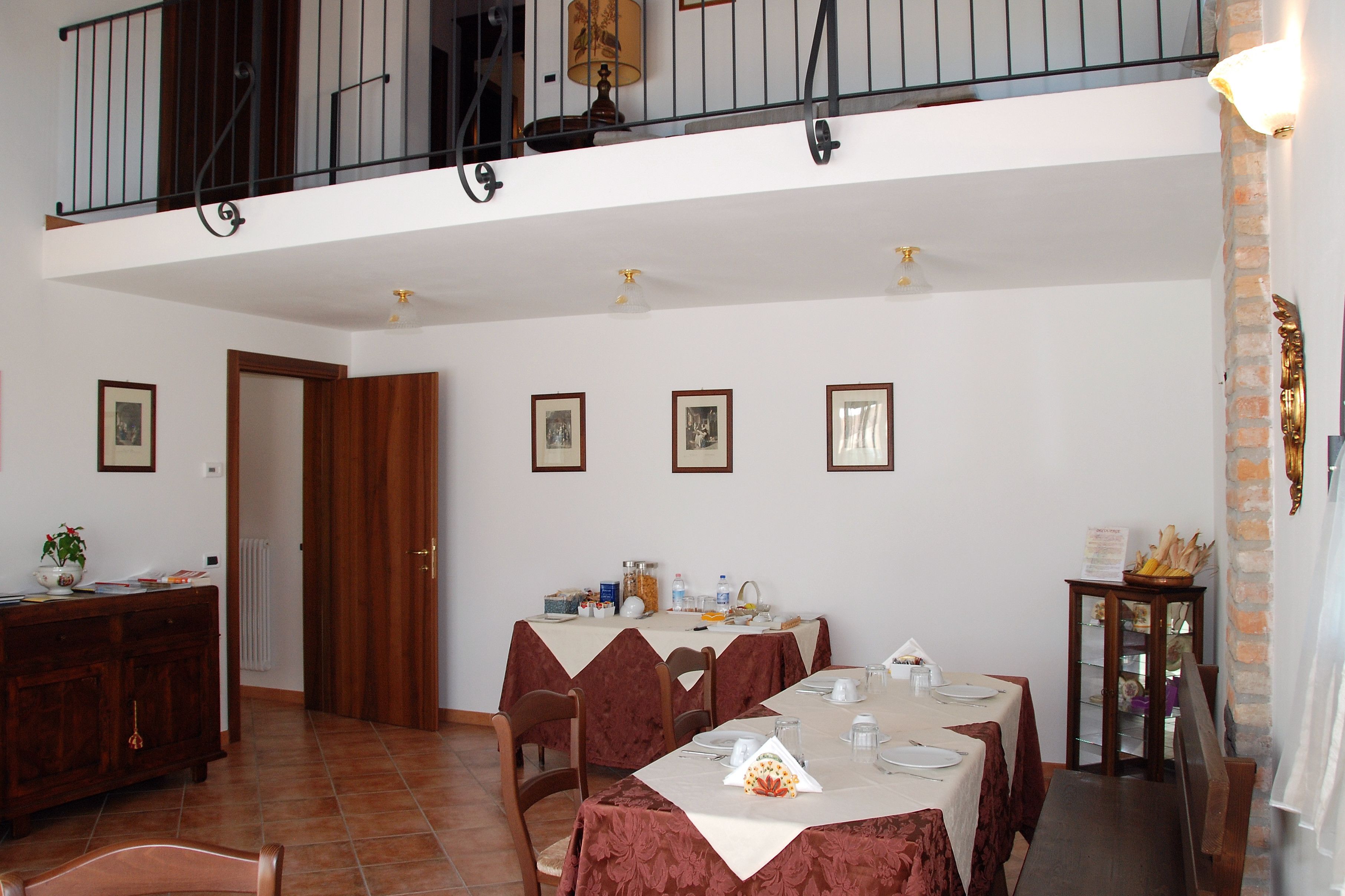 A dining area with a high ceiling, a balcony, and a brick wall.