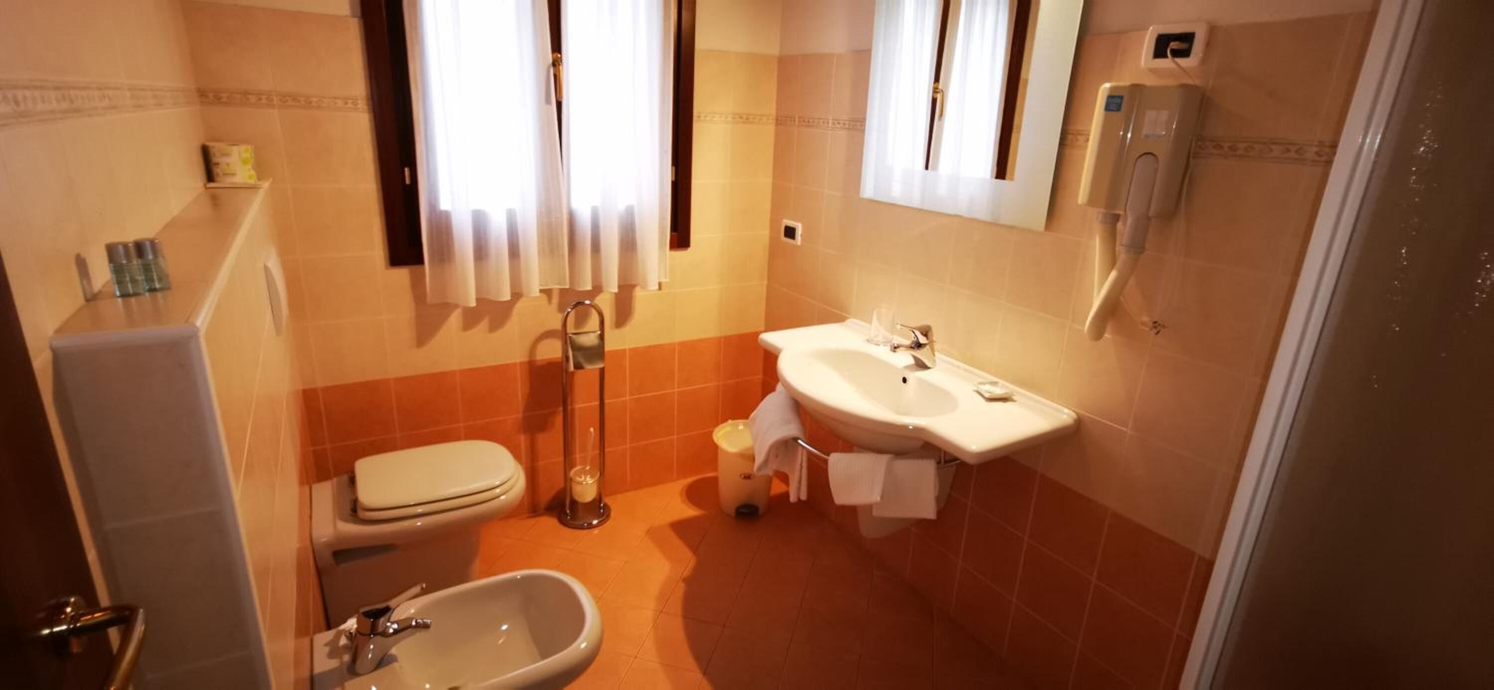 A compact bathroom with a toilet, sink, and bidet.