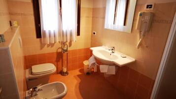 A compact bathroom with a toilet, sink, and bidet.