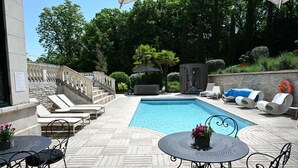 A pool area with lounge chairs, a table with chairs, and a staircase. - La Villa Eugène (Epernay)