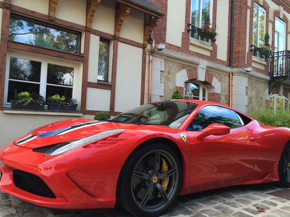 A red sports car parked in front of a building with a stone facade and multiple windows.