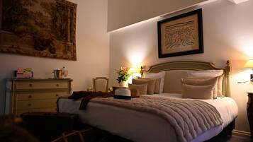 A hotel room with a large bed, a nightstand with a lamp, a dresser, and a painting on the wall.