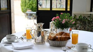 A breakfast table with croissants, orange juice, and a pitcher of coffee. - La Villa Eugène (Epernay)