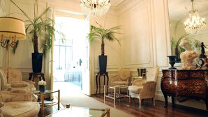 A spacious room with elegant furniture, a chandelier, and two large potted plants. - La Villa Eugène (Epernay)