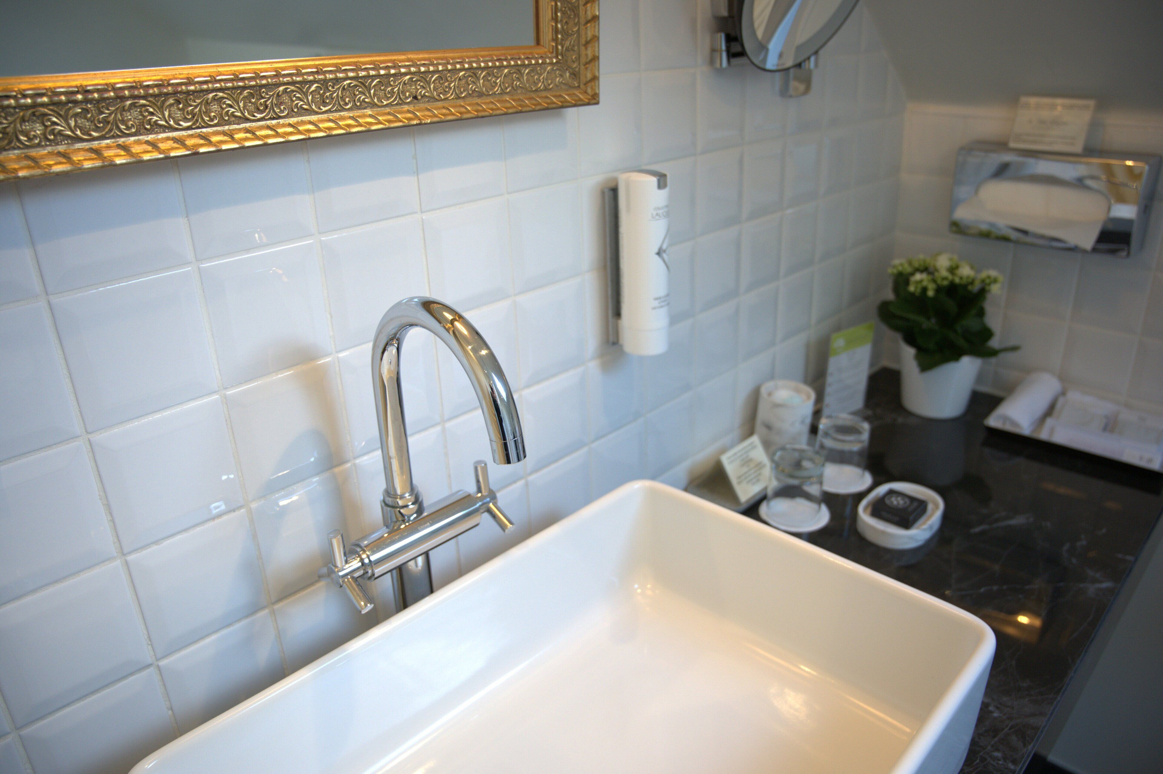 A bathroom with a white sink, a gold-framed mirror, and a towel rack.