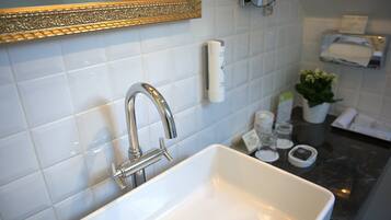 A bathroom with a white sink, a gold-framed mirror, and a towel rack.