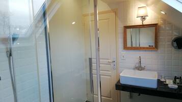 A modern bathroom with a glass shower enclosure, a white sink, and a mirror with a decorative frame.