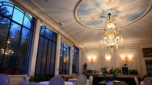 A dining room with large windows, a chandelier, and a fireplace. - La Villa Eugène (Epernay)