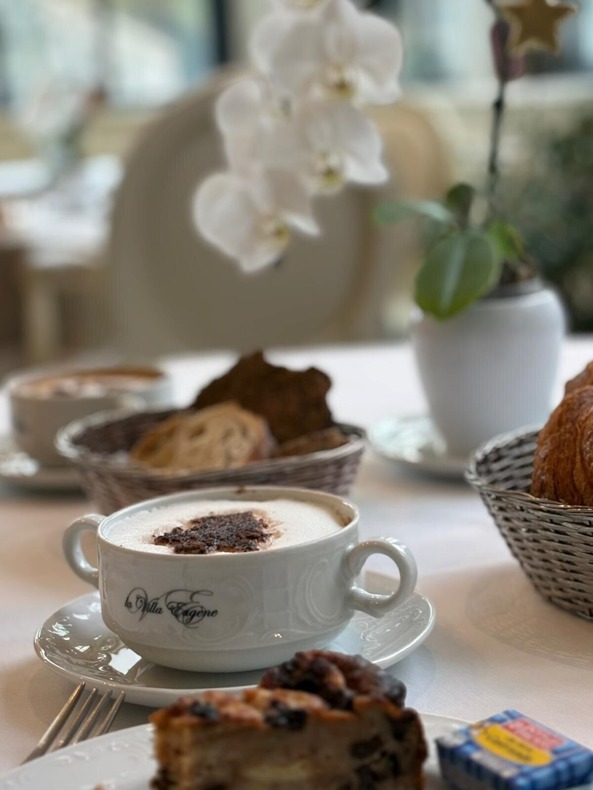 A table with a cup of coffee, a slice of cake, and a basket of bread.