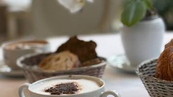 A table with a cup of coffee, a slice of cake, and a basket of bread.