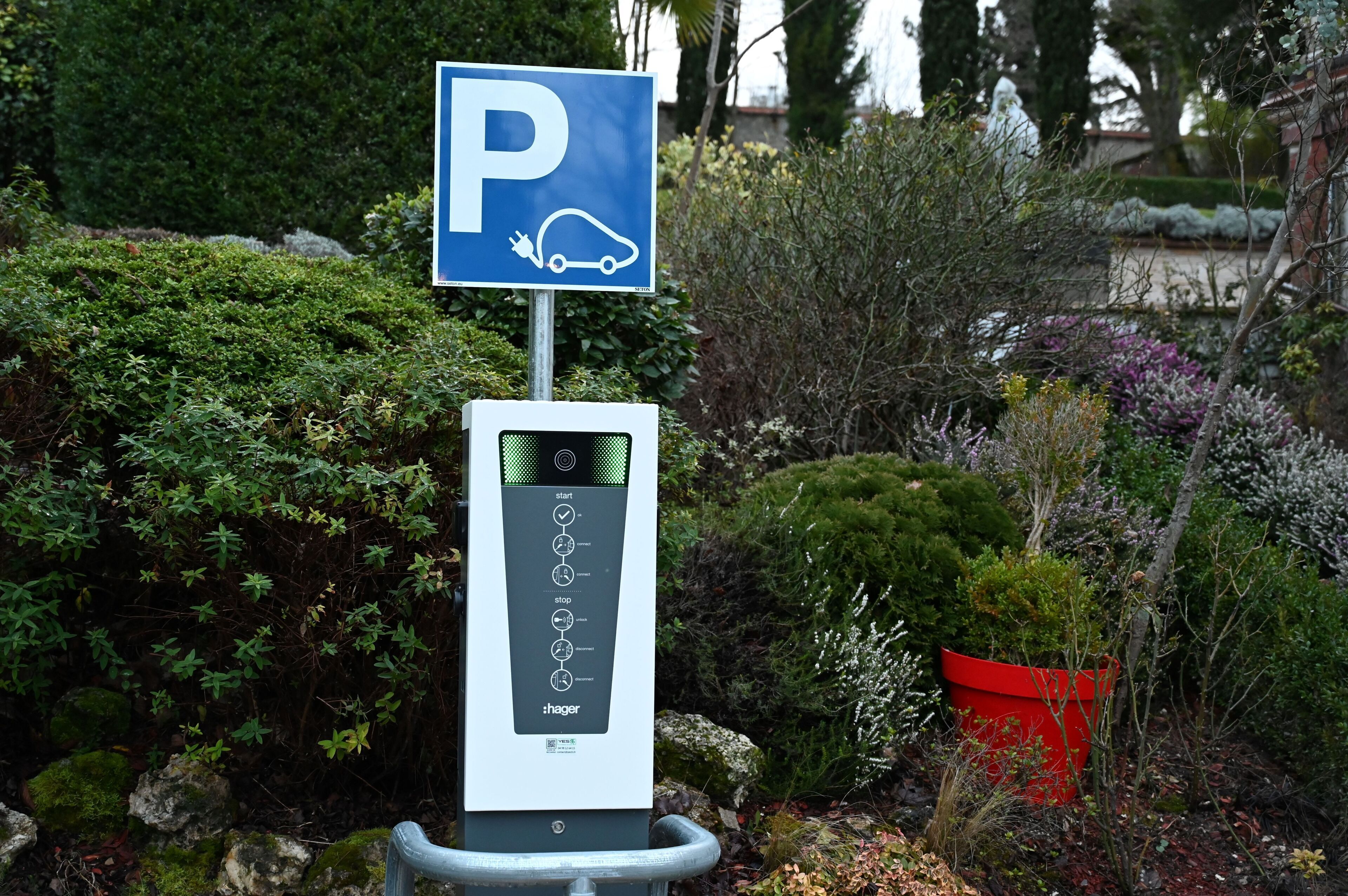 Un panneau de signalisation indiquant un espace de stationnement avec une borne de recharge.