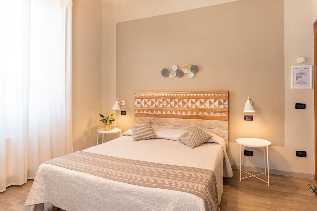 A neatly made bed with a patterned headboard, two bedside tables with lamps, and a wall-mounted decoration.