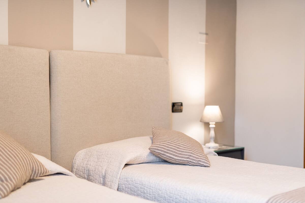 A neatly made bed with a striped pillow and a quilted blanket.