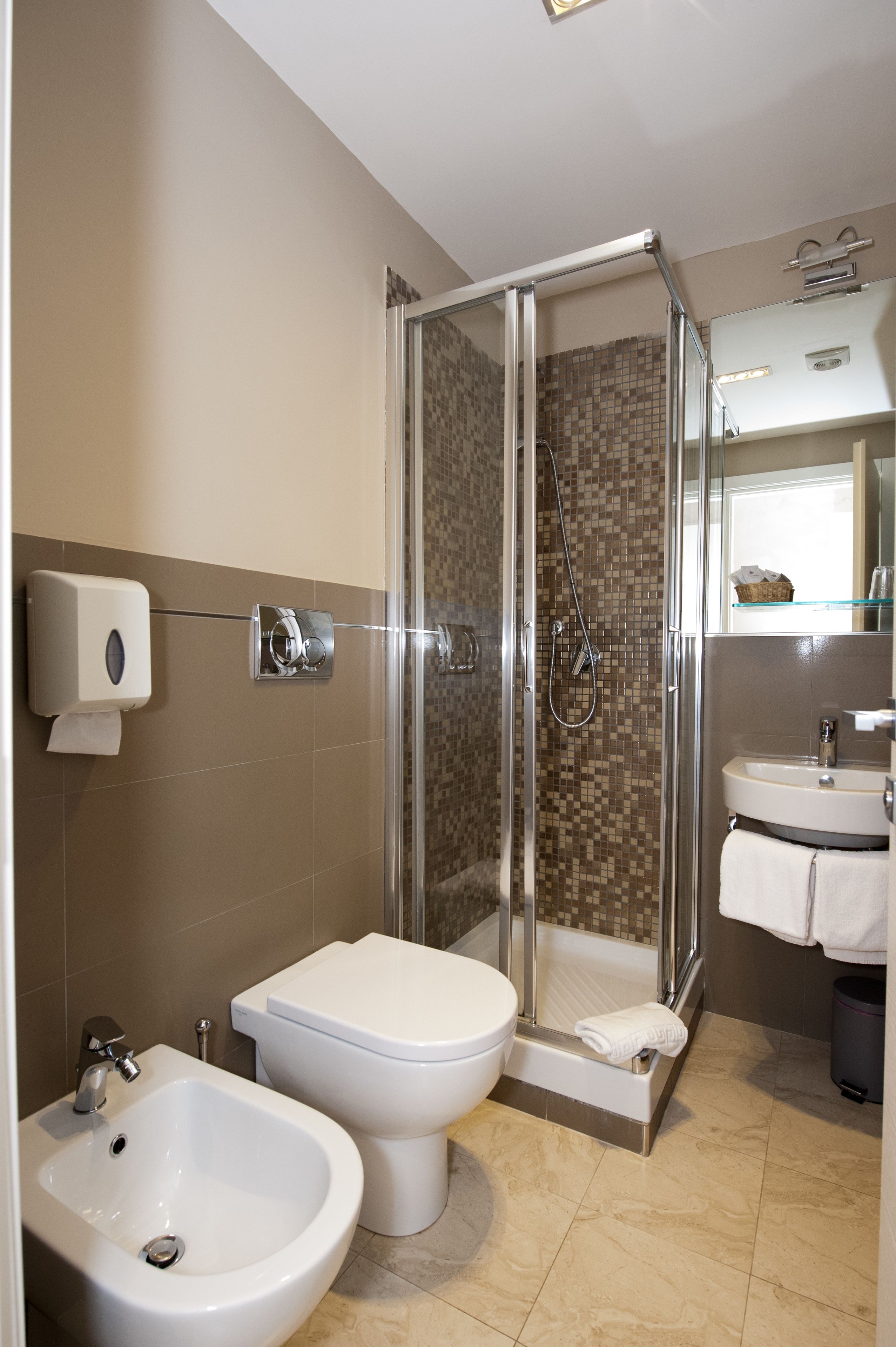 A modern bathroom with a glass-enclosed shower, a bidet, a sink, and a toilet.