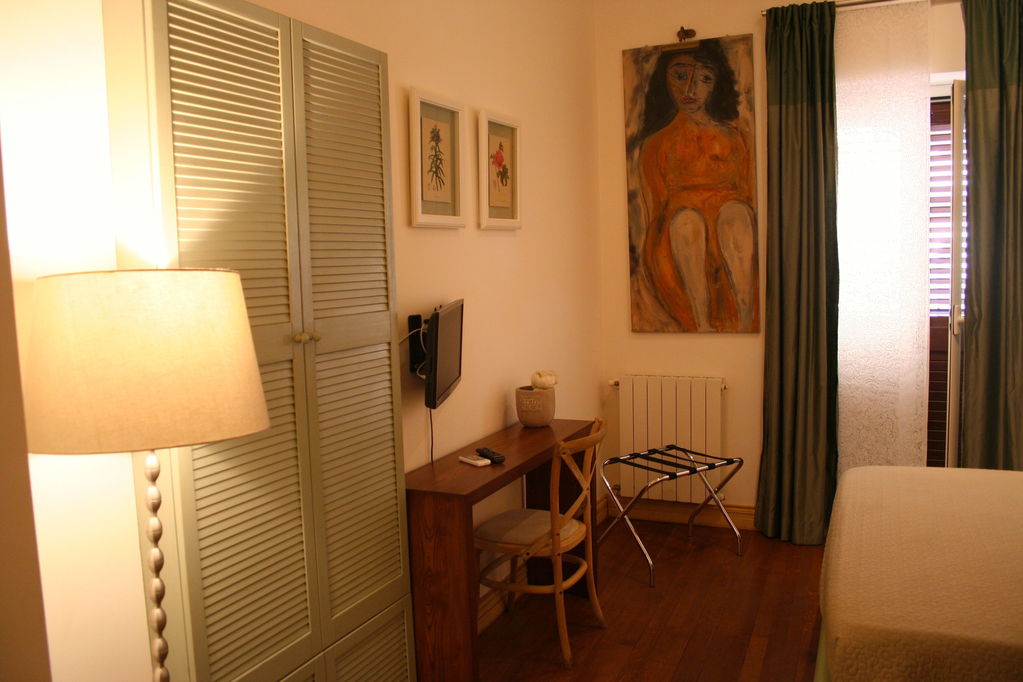 Ein Hotelzimmer mit einem Holztisch, einem Stuhl, einer Lampe, einem Bild an der Wand und einem Bett.