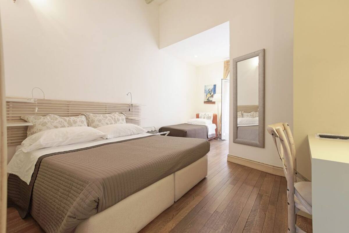 A bedroom with two beds, a desk, and a chair.