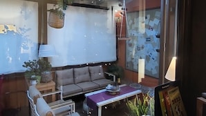 A cozy living room with a wooden ceiling, a sofa, a coffee table, and a wall with a bulletin board. - Camere a Sud (Agrigento)