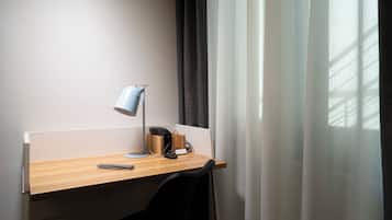 Espacio de trabajo en un hotel, con escritorio, lámpara de escritorio, teléfono y silla.
