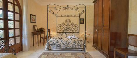 Une chambre à coucher avec un lit à baldaquin, une armoire en bois, un banc et un tapis à motifs.