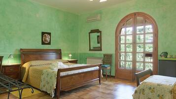 Un dormitorio con una cama de madera, una silla, una mesa y un amplio ventanal de arco.
