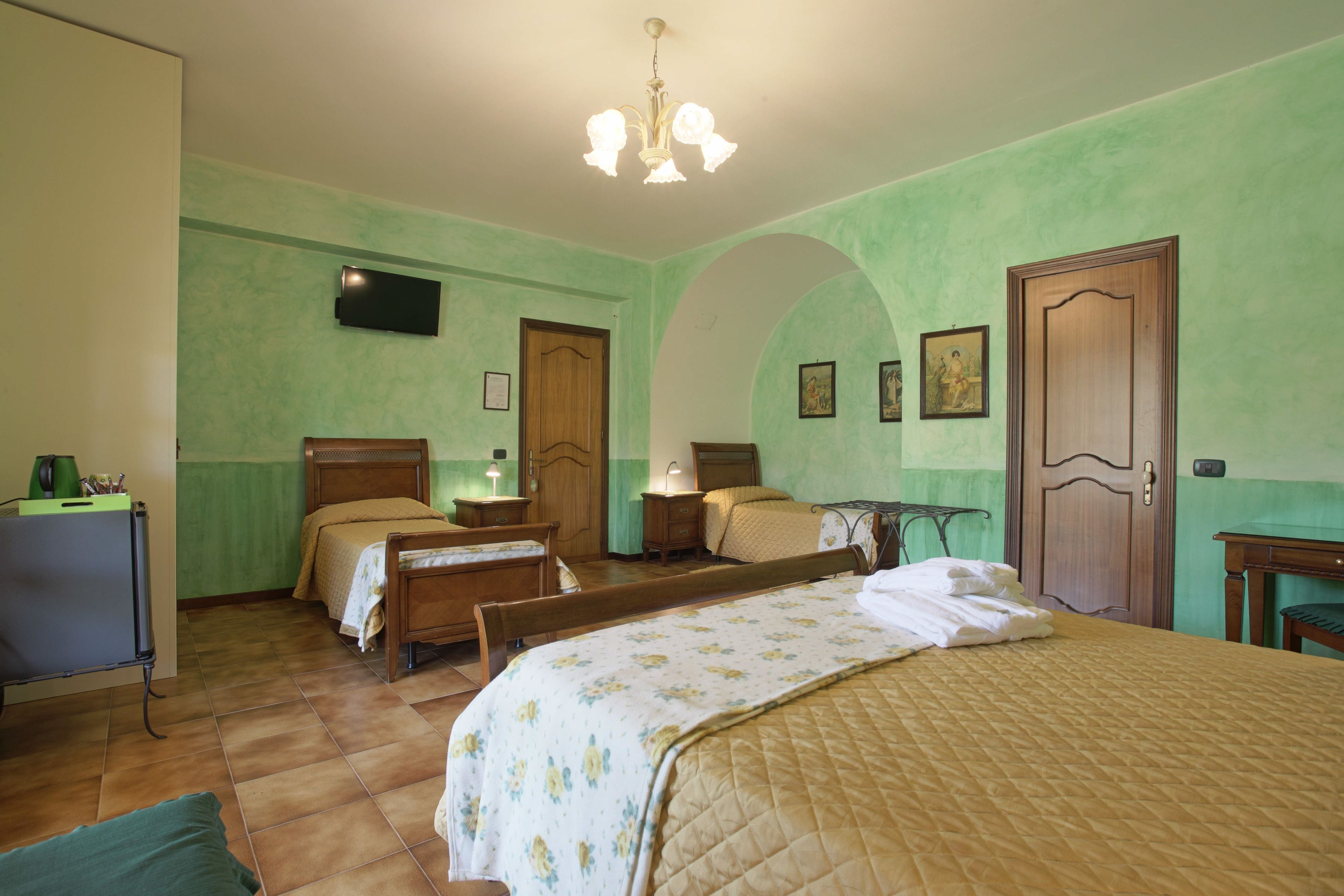 Une chambre d’hôtel avec deux lits, un bureau, une chaise, une télévision et une porte.