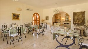 Un espace repas avec des tables dressées pour le repas, des chaises, des lustres et une grande fenêtre.