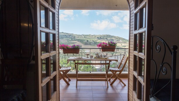 Un balcon avec une table et des chaises, donnant sur un paysage pittoresque.