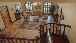 Un vaste salon agrémenté d’un grand tapis, de canapés en cuir, d’une table basse et d’un escalier menant à l’étage supérieur.