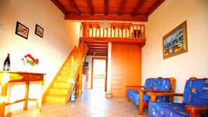 Uma sala de estar espaçosa com escada de madeira, um conjunto de sofá e uma área de jantar com mesa e cadeiras.
