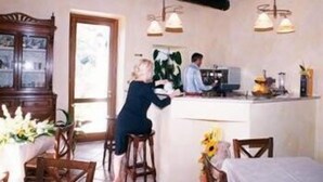 A cozy kitchen with wooden furniture, a dining area with a table set for two, and a large window providing natural light. - Casale 900 (Capaccio-Paestum)