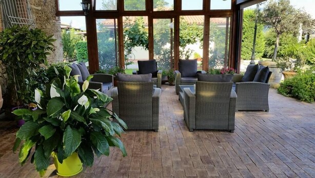 A covered outdoor seating area with wicker furniture and potted plants. - Casale 900 (Capaccio-Paestum)